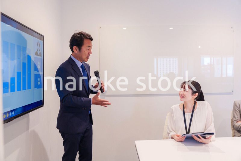 会議で資料を見ながらプレゼンをする中年のオフィスワーカー