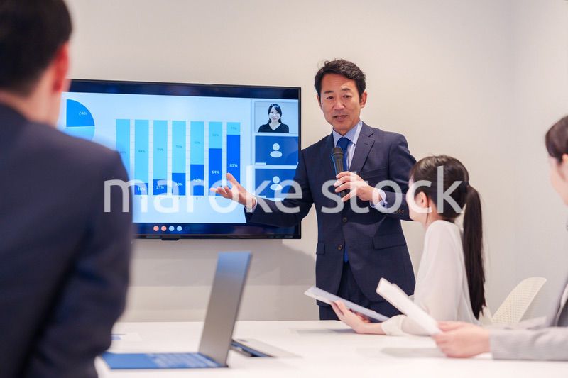 会議で資料を見ながらプレゼンをする中年のオフィスワーカー