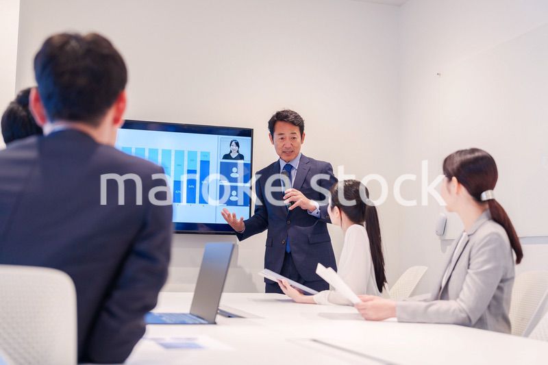 会議で資料を見ながらプレゼンをする中年のオフィスワーカー