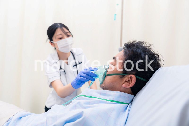 人工呼吸器をつけた患者のケアをする看護師の女性