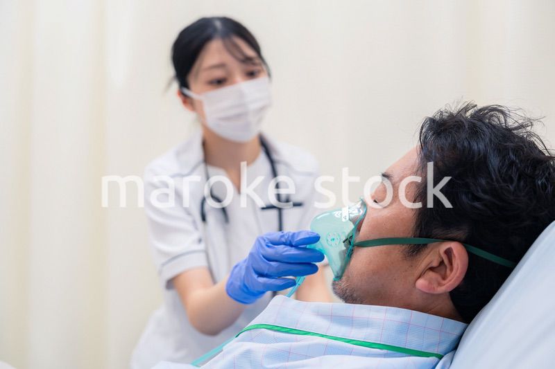 人工呼吸器をつけた患者のケアをする看護師の女性