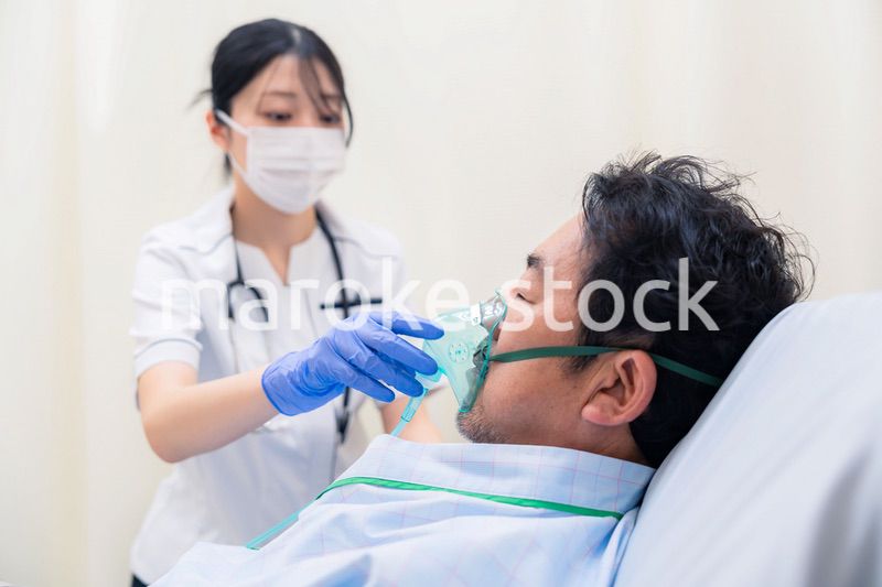 人工呼吸器をつけた患者のケアをする看護師の女性