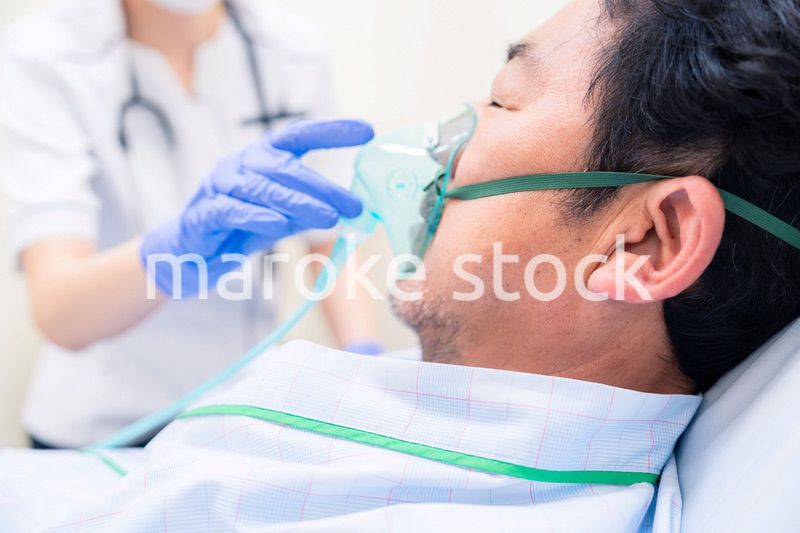 人工呼吸器をつけた患者のケアをする看護師の女性