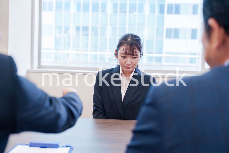 オフィスで上司に詰められて悲しい表情をする女性社員