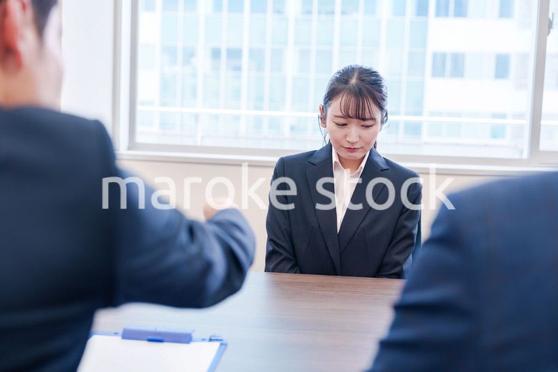 オフィスで上司に詰められて悲しい表情をする女性社員