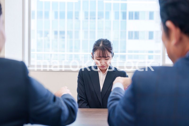 オフィスで上司に詰められて悲しい表情をする女性社員
