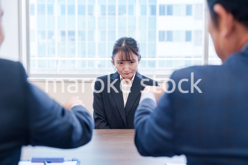 オフィスで上司に詰められて悲しい表情をする女性社員