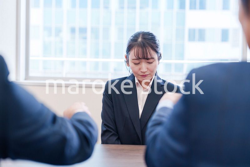 オフィスで上司に詰められて悲しい表情をする女性社員