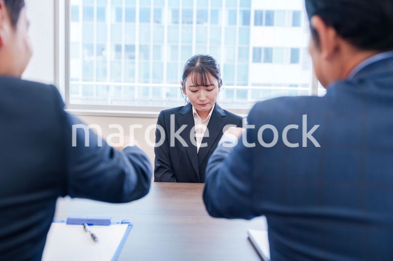 オフィスで上司に詰められて悲しい表情をする女性社員