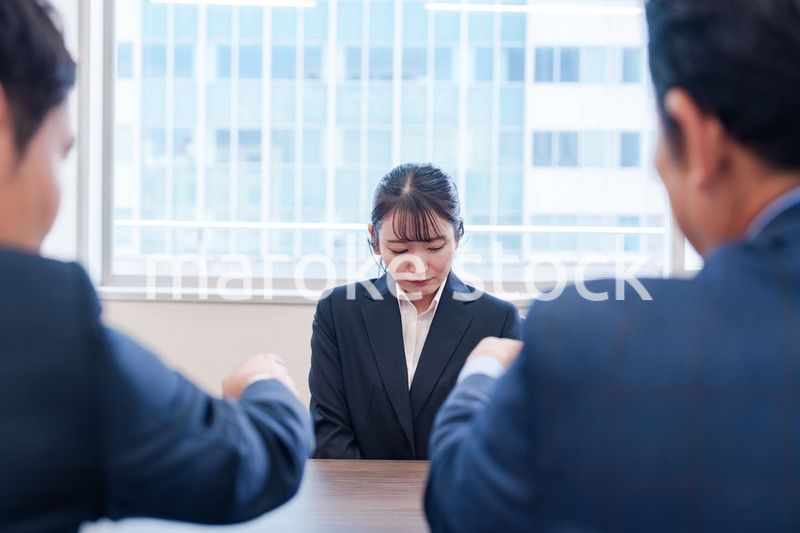 オフィスで上司に詰められて悲しい表情をする女性社員