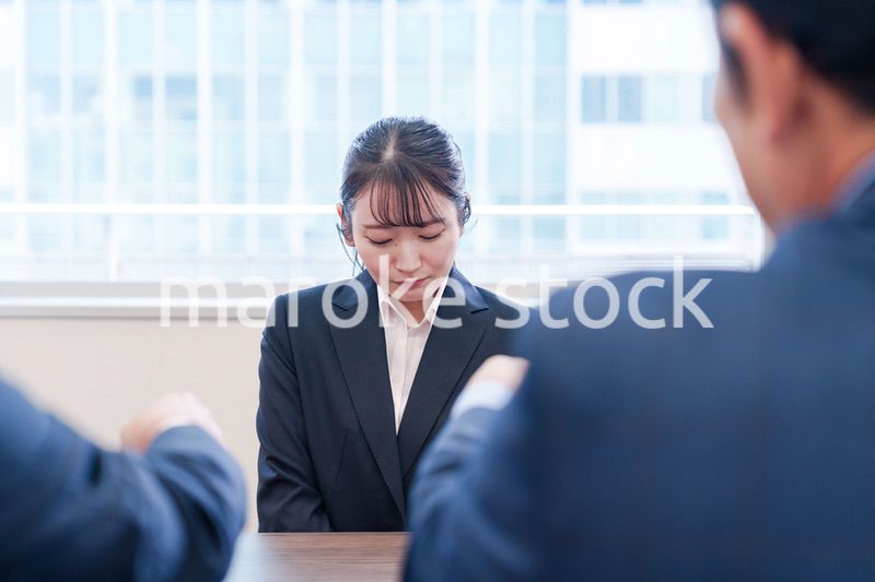 オフィスで上司に詰められて悲しい表情をする女性社員