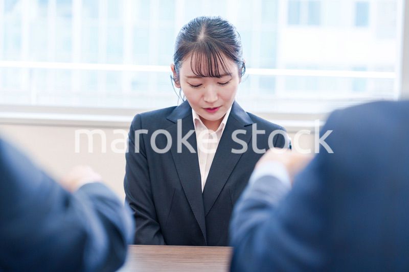 オフィスで上司に詰められて悲しい表情をする女性社員