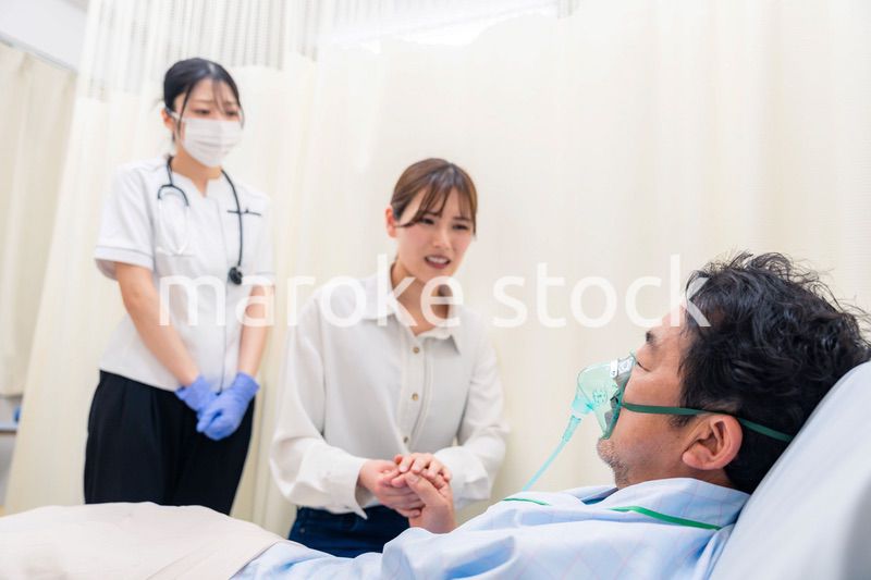 人工呼吸器をつけた家族のお見舞いをする若い女性