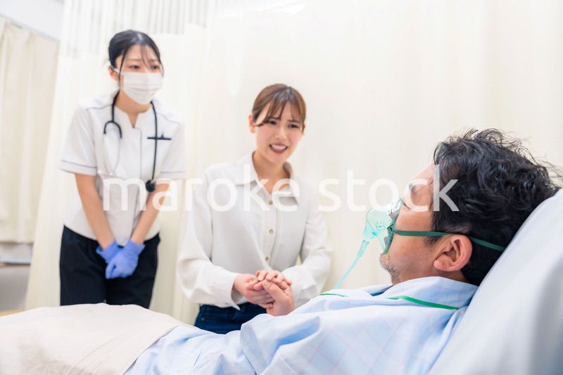 人工呼吸器をつけた家族のお見舞いをする若い女性