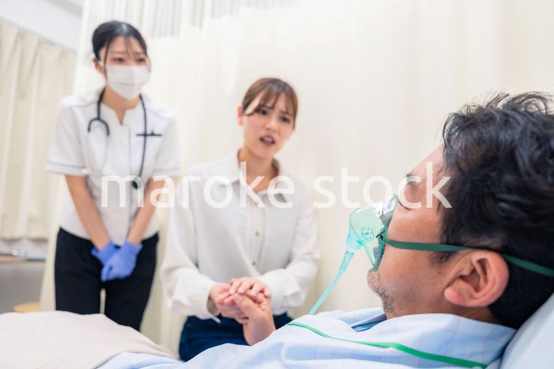 人工呼吸器をつけた家族のお見舞いをする若い女性