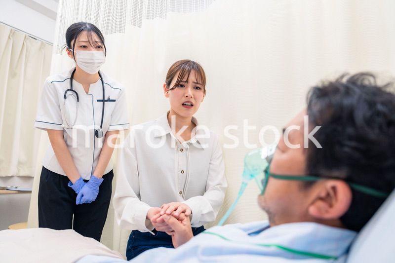 人工呼吸器をつけた家族のお見舞いをする若い女性
