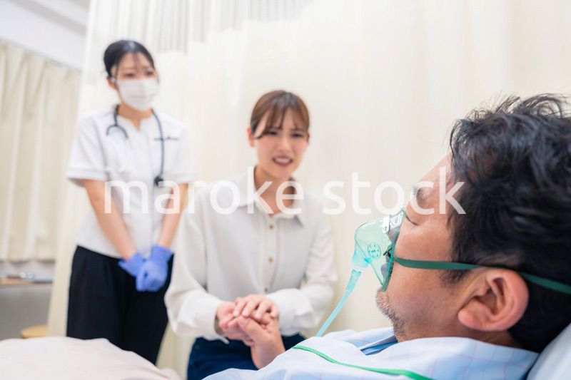 人工呼吸器をつけた家族のお見舞いをする若い女性