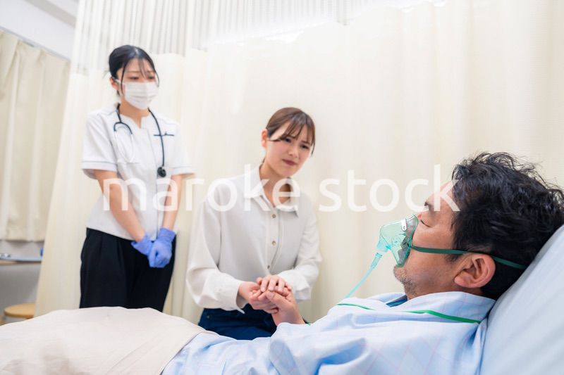 人工呼吸器をつけた家族のお見舞いをする若い女性