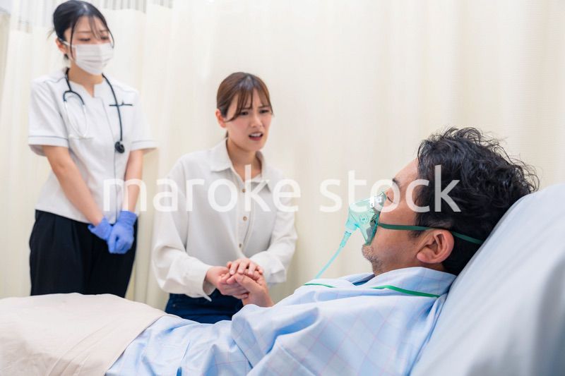 人工呼吸器をつけた家族のお見舞いをする若い女性