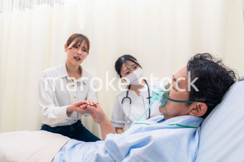 人工呼吸器をつけた家族のお見舞いをする若い女性