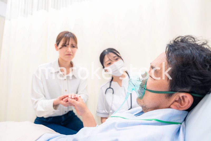 人工呼吸器をつけた家族のお見舞いをする若い女性