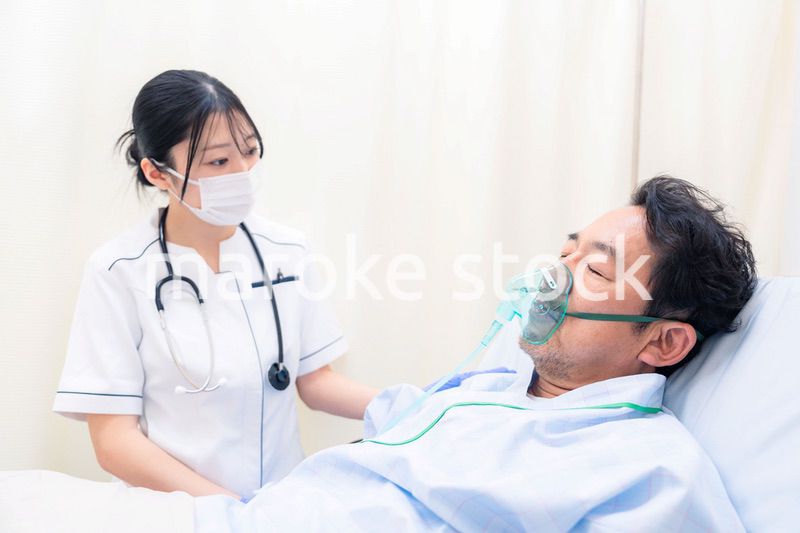 人工呼吸器をつけた患者のケアをする看護師の女性