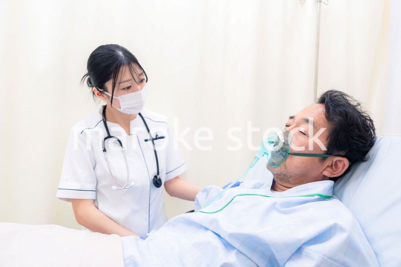 人工呼吸器をつけた患者のケアをする看護師の女性