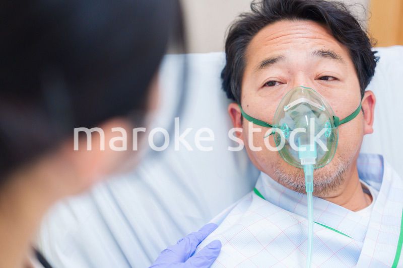 人工呼吸器をつけて話をする入院患者の男性