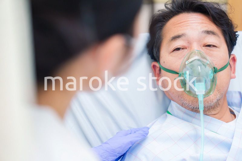 人工呼吸器をつけて話をする入院患者の男性
