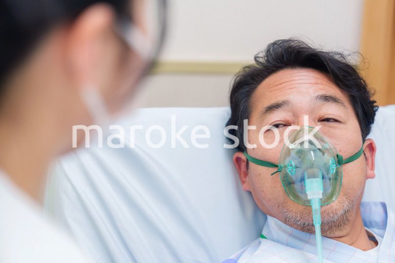 人工呼吸器をつけて話をする入院患者の男性
