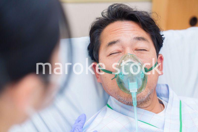 人工呼吸器をつけて話をする入院患者の男性