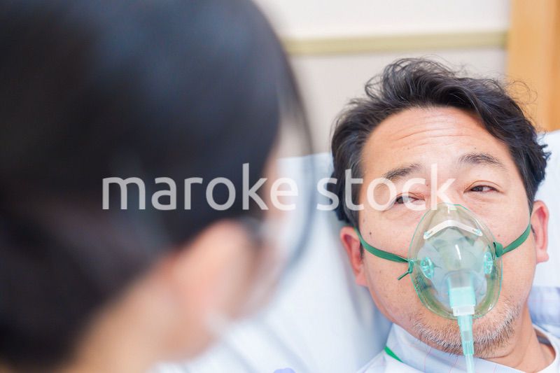 人工呼吸器をつけて話をする入院患者の男性