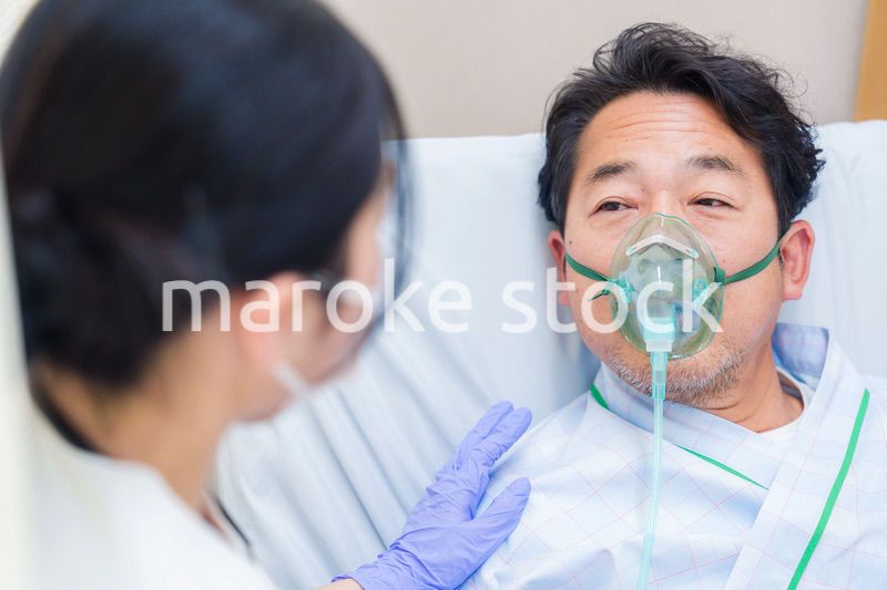 人工呼吸器をつけて話をする入院患者の男性