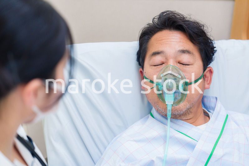 人工呼吸器をつけて話をする入院患者の男性