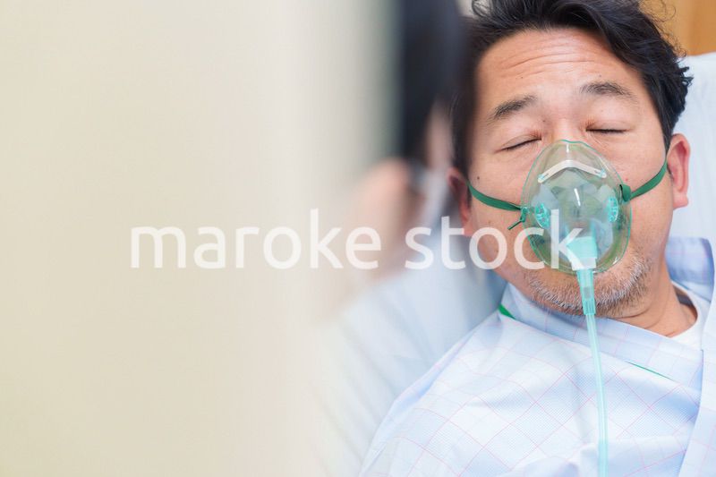 人工呼吸器をつけて話をする入院患者の男性