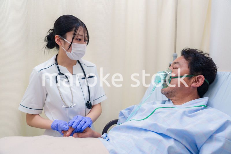 看護師の手を握る入院患者の男性