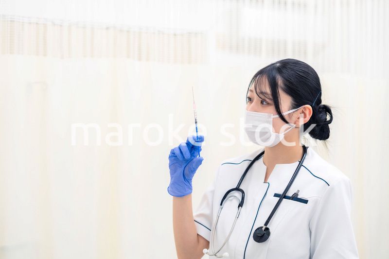注射器を持つ若い女性の医療従事者