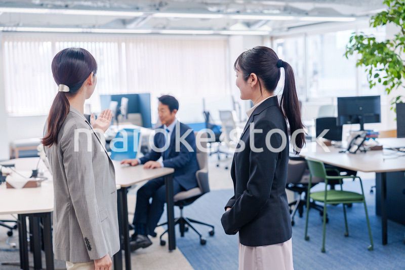 先輩社員にオフィスを案内してもらうフレッシュな女性