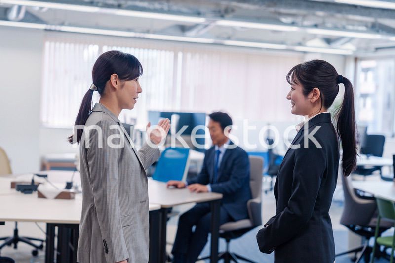 先輩社員にオフィスを案内してもらうフレッシュな女性