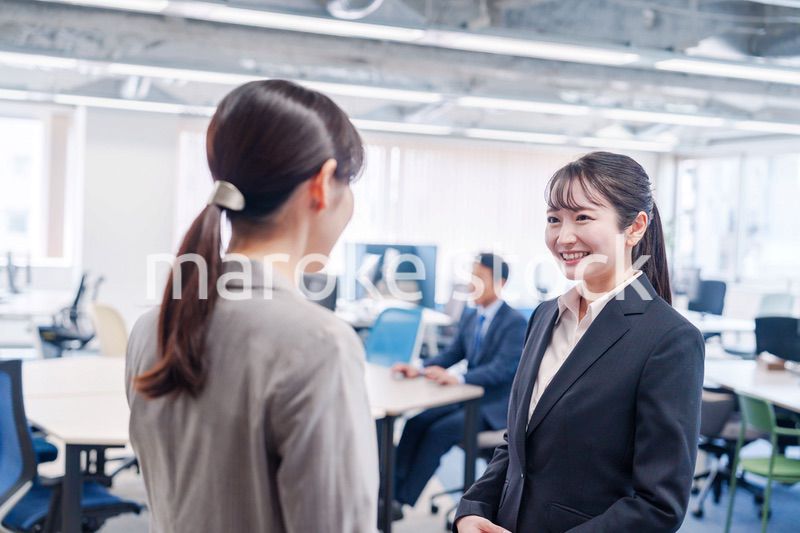 先輩社員にオフィスを案内してもらうフレッシュな女性