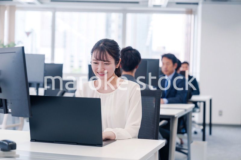 オフィスで笑顔でデスクワークをする若い女性