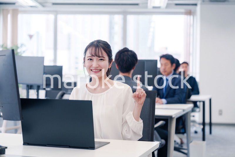 オフィスでデスクワークをしながら指を指す若いビジネスウーマン