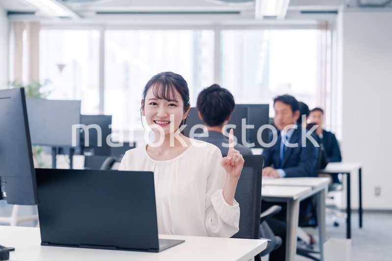 オフィスでデスクワークをしながら指を指す若いビジネスウーマン
