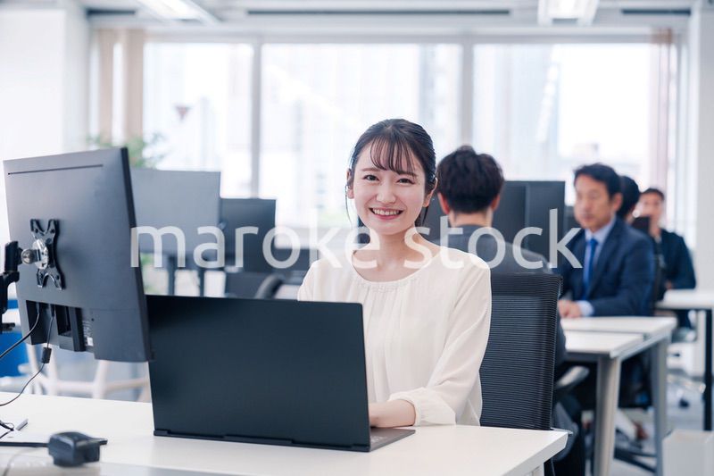 オフィスで笑顔でデスクワークをする若い女性