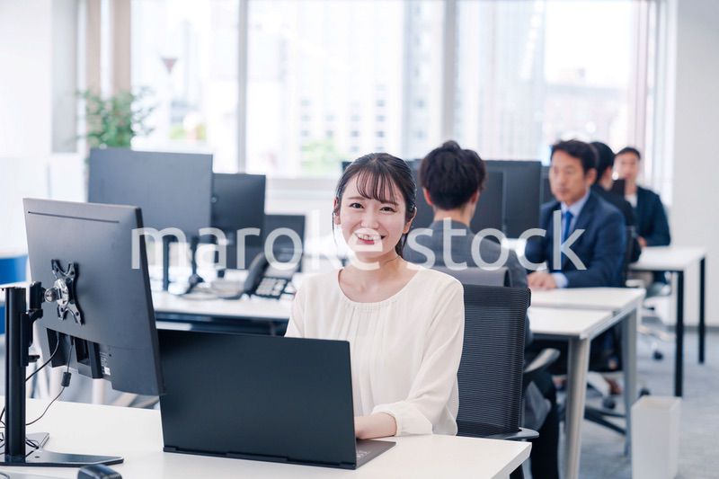 オフィスで笑顔でデスクワークをする若い女性