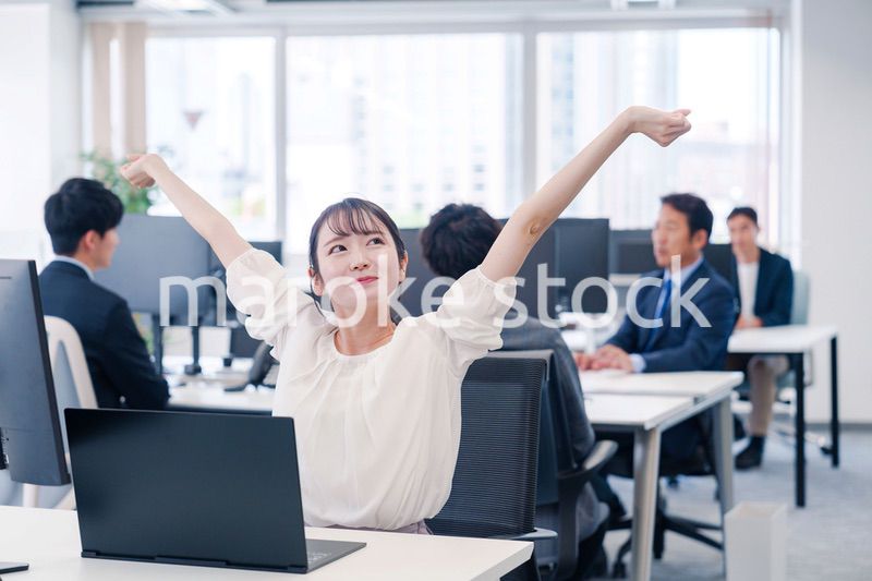 オフィスで伸びをしてリフレッシュするビジネスウーマン