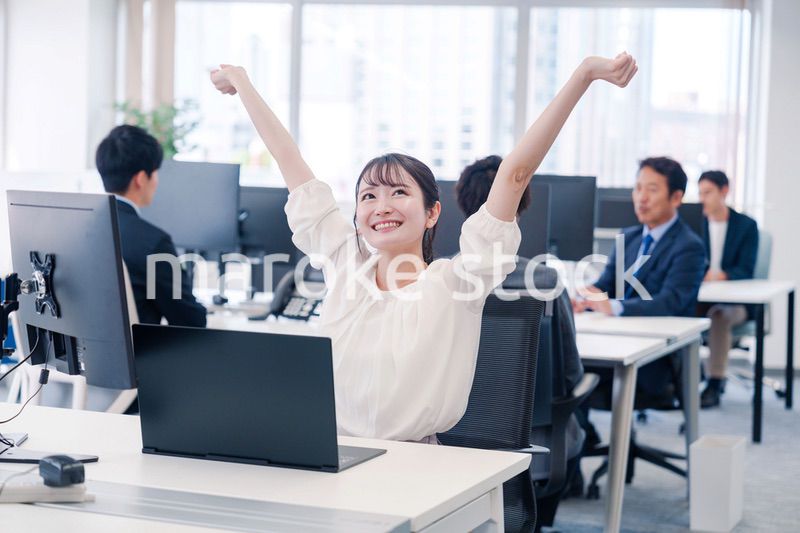 オフィスで伸びをしてリフレッシュするビジネスウーマン