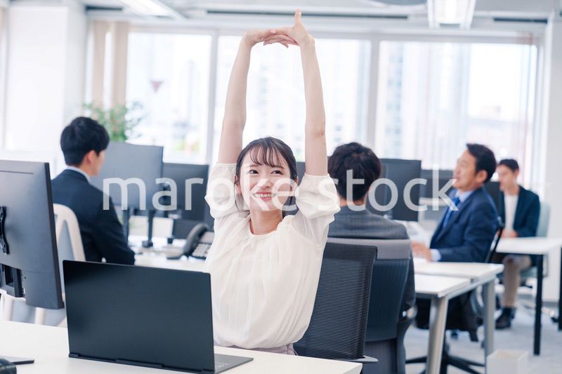 オフィスで伸びをしてリフレッシュするビジネスウーマン