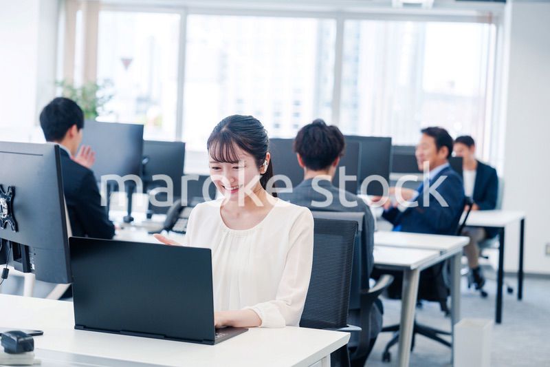 ワイヤレスイヤホンを使いオフィスでリモート会議をする女性