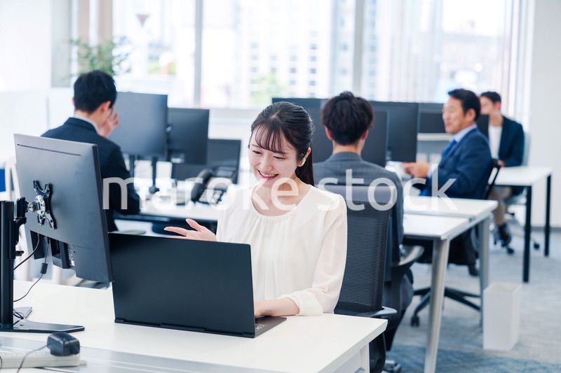 ワイヤレスイヤホンを使いオフィスでリモート会議をする女性